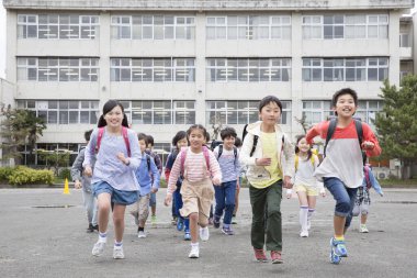 Okuldan sonra koşan bir grup mutlu Asyalı çocuk.  