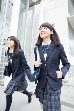 Okul çantalı Asyalı kızlar şehirde yürüyor. 