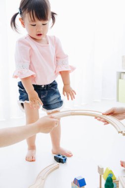 Küçük tatlı Japon kız oturma odasında oyuncaklarla oynuyor.