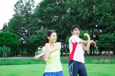 Sportif genç Asyalı çift parkta koşmadan önce geriniyor.