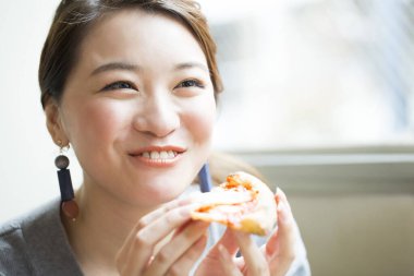 Restoranda pizza yiyen kadın.