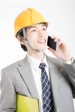 Genç Japon iş adamının yakın plan portresi. Kasketli ve telefonla konuşuyor.