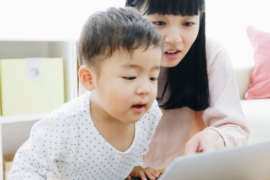 Genç anne ve oğlu evde dizüstü bilgisayar kullanıyor..