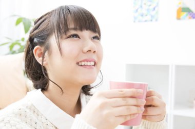 Güzel genç bayan evde çay içiyor.