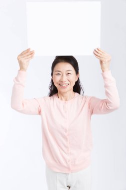 Beyaz arka planda beyaz pankart tutan yaşlı Asyalı kadın izole edildi 