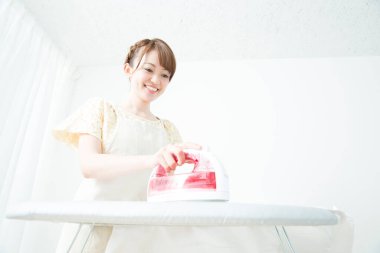 Giysileri ütüleyen genç kadın.