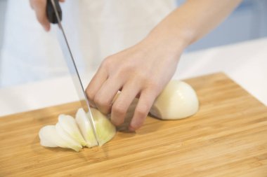 female chef chopping onion in kitchen