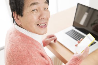 Akıllı telefon ve dizüstü bilgisayar kullanan Asyalı bir işadamının portresi 