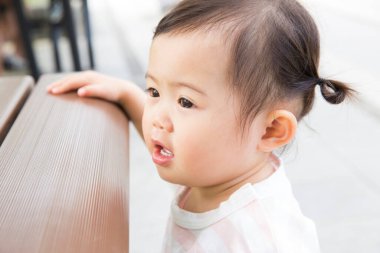 Küçük kız dikiliyor ve başka tarafa bakıyor. 