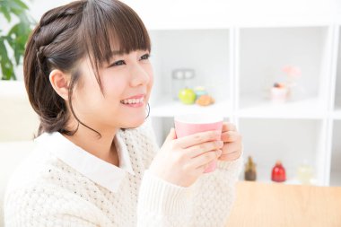 Güzel genç bayan evde çay içiyor.