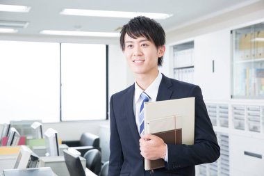 Genç Asyalı işadamı ofiste duruyor.