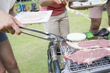 Bahçede yemek yapan genç bir çift.