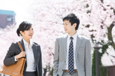 Şehir caddesinde kiraz çiçekleri olan iki Japon iş adamı.