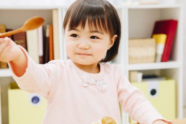 Mutfakta kaşığı olan Asyalı kız.