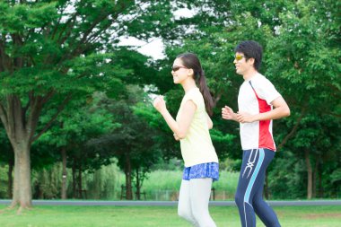 Sportif genç Asyalı çift parkta koşuyor.