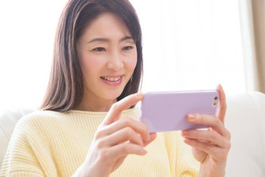 Asyalı kadın akıllı telefonuyla selfie çekiyor. 