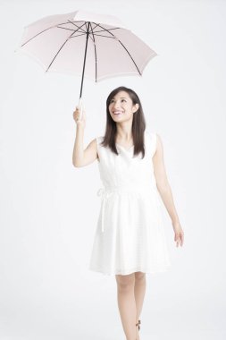 Beyaz arka planda şemsiye tutan güzel Asyalı kadın. 