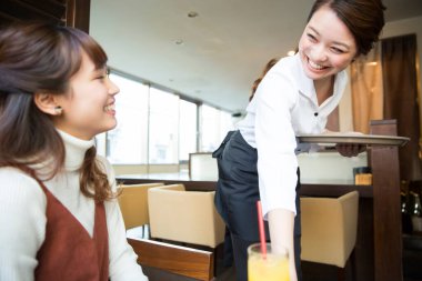 Genç bir kadın kahvaltı yapıyor, garson masasına servis yapıyor. 