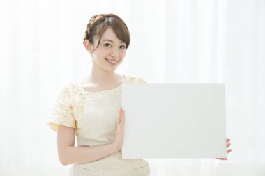 Genç ve güzel bir kadın beyaz bir tahta tutuyor.