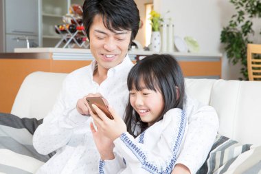 Genç bir aile evde akıllı telefon oynuyor. 