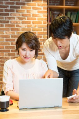 Genç Asyalı çift ofiste dizüstü bilgisayar kullanıyor. 