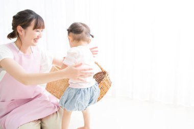 Genç Asyalı anne ve küçük kızı sepetlerle oynuyorlar. 