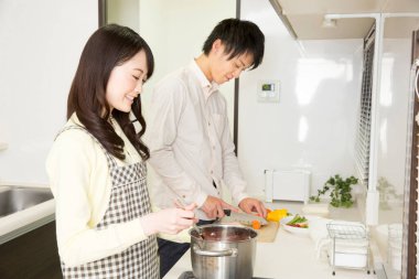 Genç Asyalı çift mutfakta birlikte yemek pişiriyor.