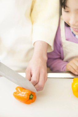 Genç anne ve kız mutfakta taze salata hazırlıyorlar. 