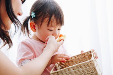 Anne ve küçük kızı sepet ve oyuncaklarla oynuyorlar. 