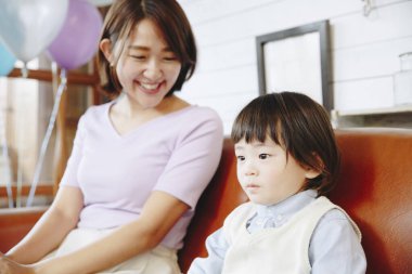 Kanepede Asyalı genç anne ve oğlunun portresi. 