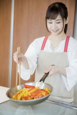 Genç Japon kadının portresi mutfakta yemek hazırlıyor. 