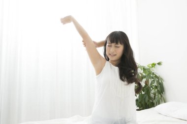 Genç bir kadın sabah yatağında uyanıyor.