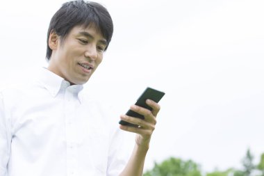 Genç Asyalı adam cep telefonu kullanıyor.