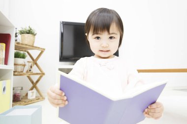 Küçük Çinli kız kitap okuyor.