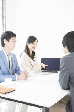 Genç Japon iş adamları ofiste dizüstü bilgisayarla çalışıyorlar.