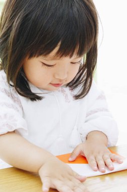 Asyalı bebek kağıtla oynuyor. 