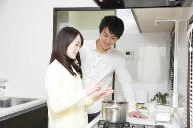 Genç Asyalı çift mutfakta birlikte yemek pişiriyor.