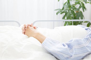 Hastane yatağında uzanmış el ele tutuşan biri.