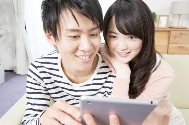 Mutlu Asyalı çift evde tablet kullanıyor.