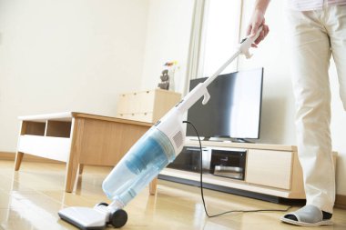 Adam evde elektrikli süpürgeyle temizlik yapıyor.