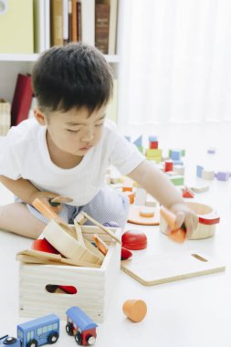 Küçük çocuk yerde oyuncaklarla oynuyor.