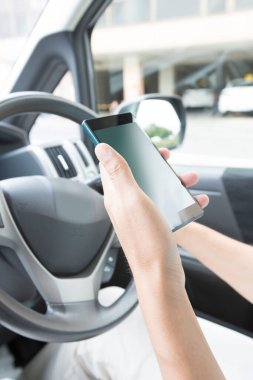 Kadın arabada akıllı telefonu tutuyor.