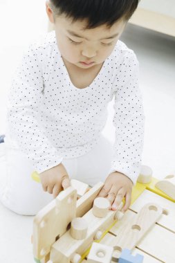 Küçük Asyalı kız ahşap oyuncaklarla oynuyor.