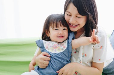 Evdeki oturma odasında annesiyle oynayan tatlı Asyalı küçük kız.