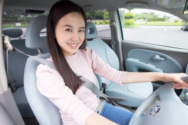 Genç mutlu Asyalı kadın arabasını kullanıyor.
