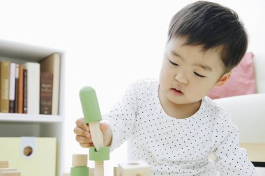 Küçük Asyalı kız ahşap oyuncaklarla oynuyor.