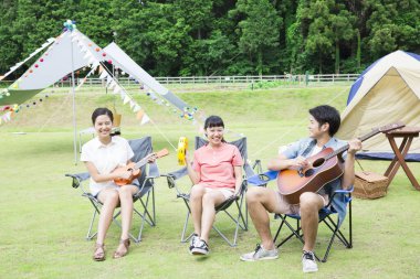 Mutlu Asyalı arkadaşlar kamp parkında müzik aletleri çalıyorlar.