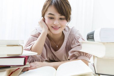 Asyalı kız öğrenci kitap okuyor.