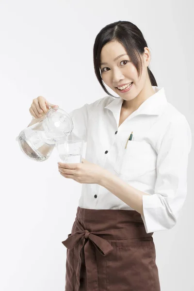 Vrolijk Aziatische Serveerster Gieten Water Van Kruik Glas — Stockfoto