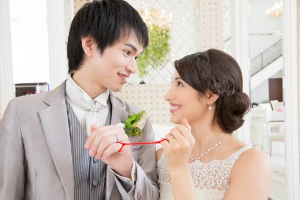 赤いひもで結ばれた指が付いている美しい幸せな若い結婚式のカップル — ストック写真